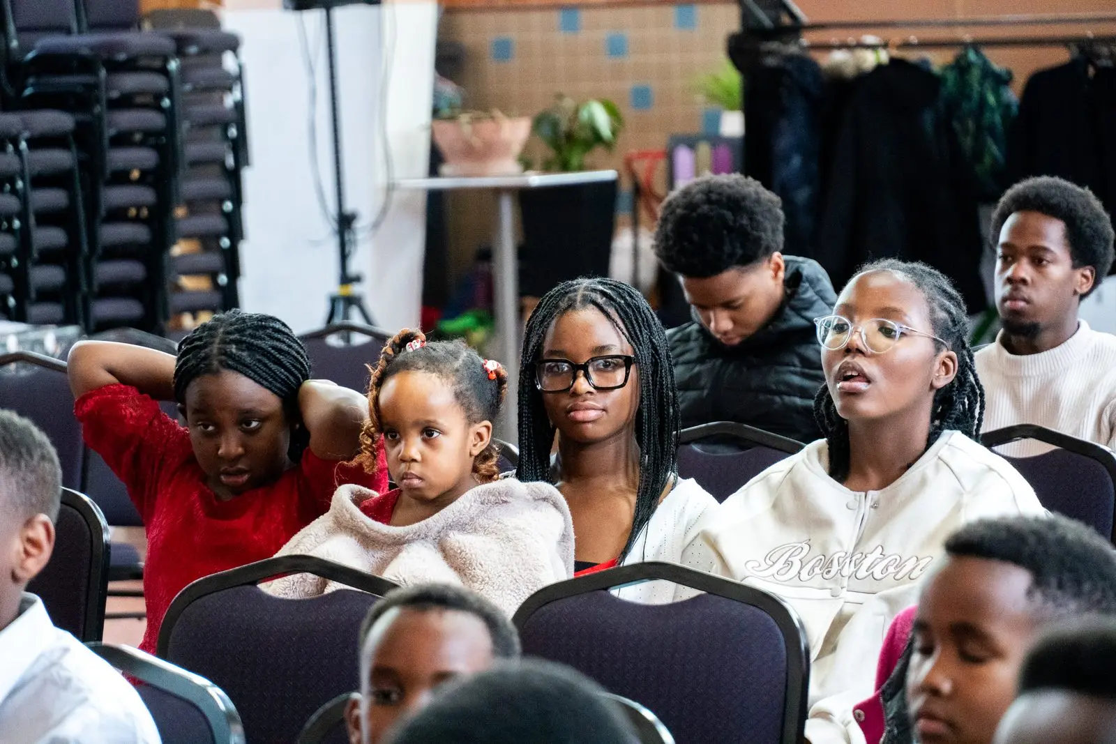 Des adolescents et des enfants assis dans l'assemblée, attentifs.
