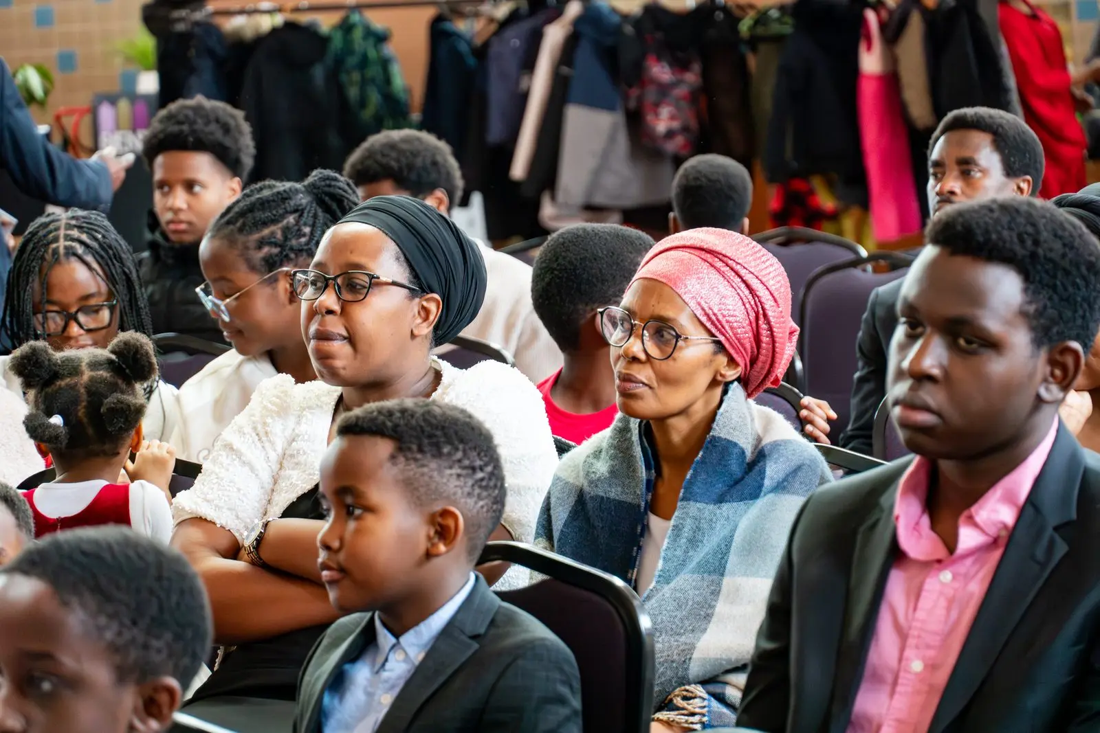 Women, teenagers and children seated side by side, listening during the service.