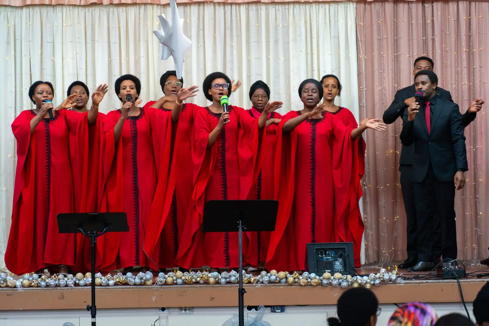 La chorale en rouge lève les mains dans l'adoration en chantant.