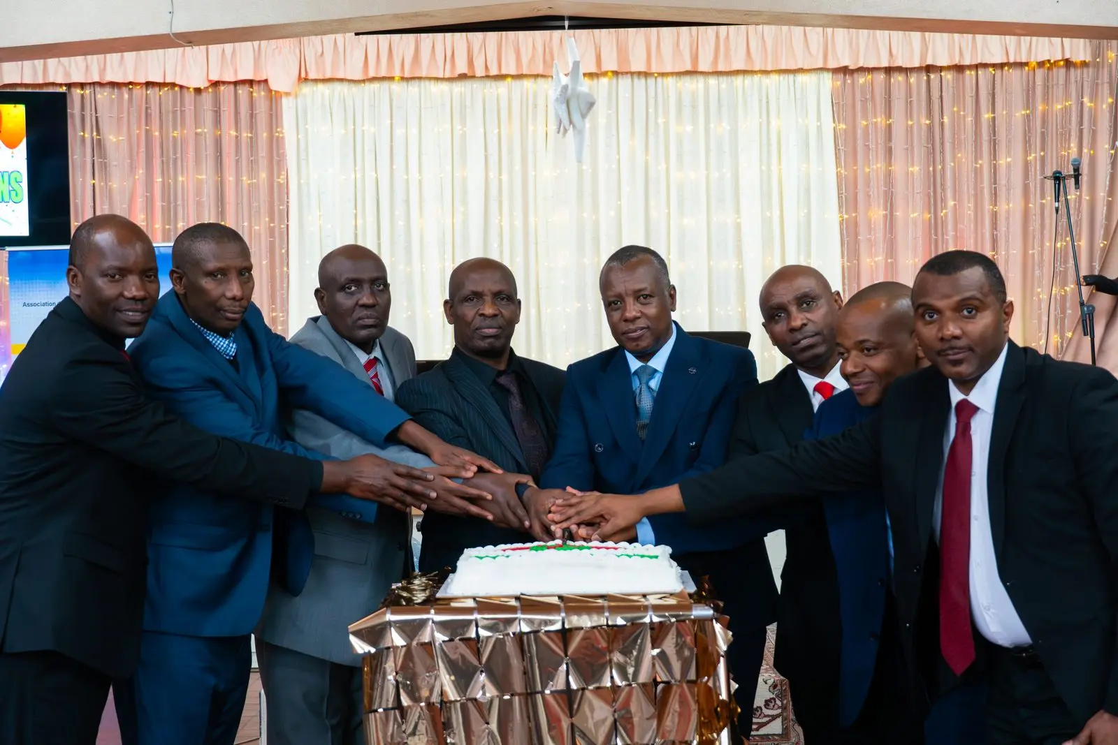 Church leaders gathered around the celebration cake, hands joined on the knife.
